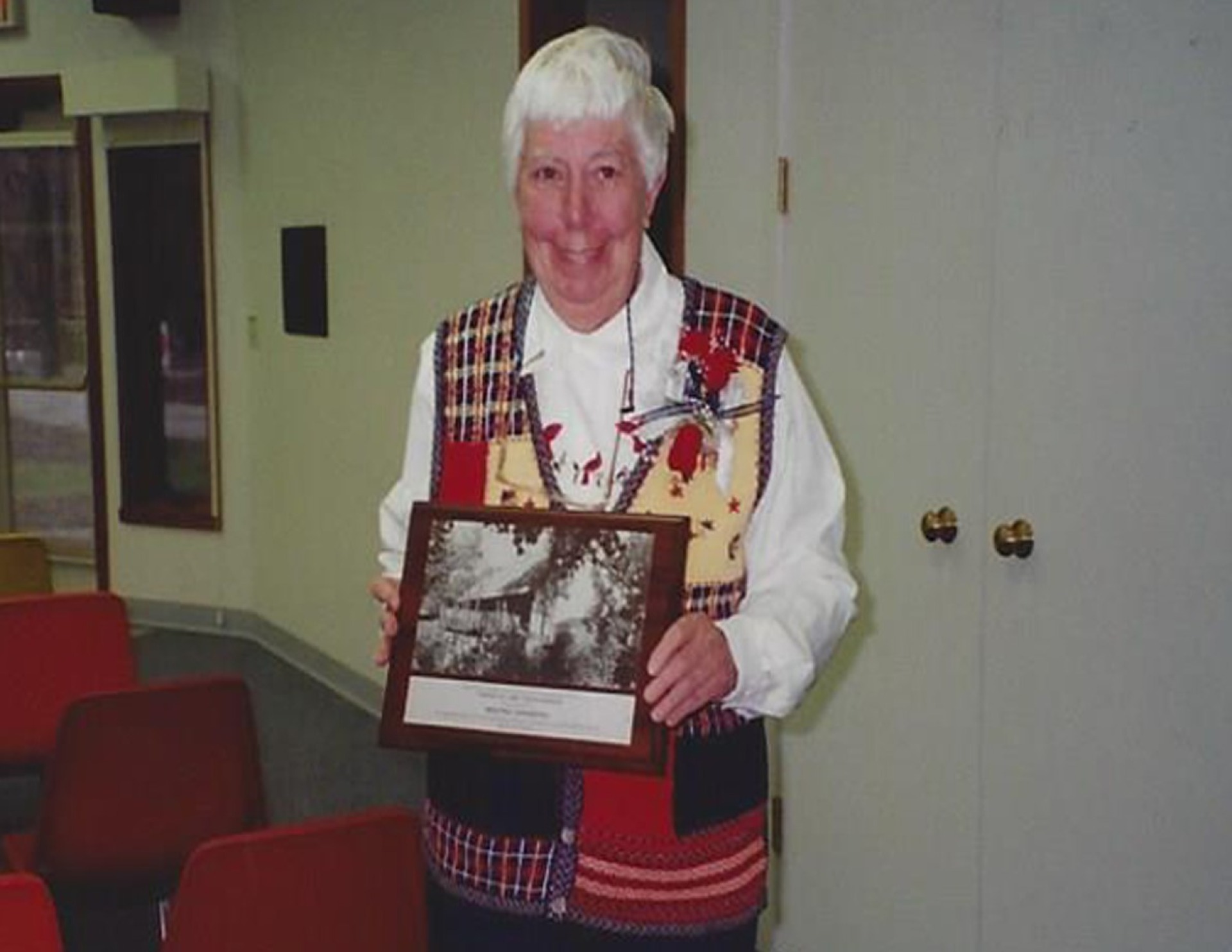 Maxine Sanberg proudly displaying a plaque.